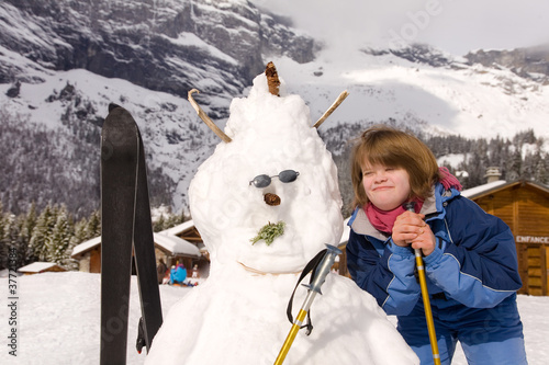 A girl with Down Syndrome and her snowman.