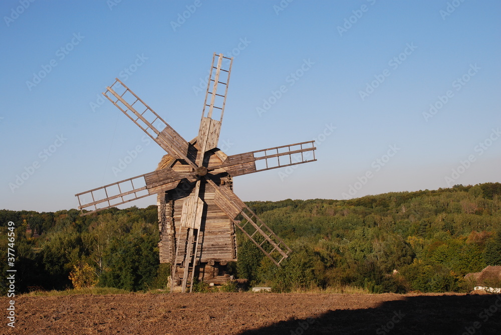 Old windmill standing alone in the field with the blue sky on the background with copyspace
