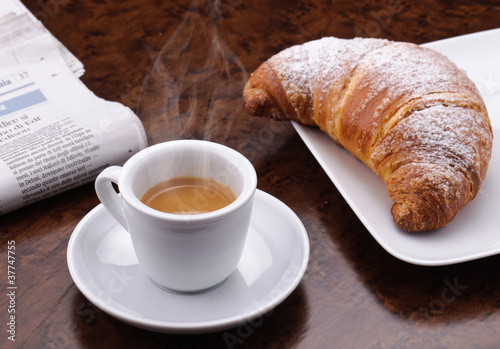Caff   fumante con croissant e giornale