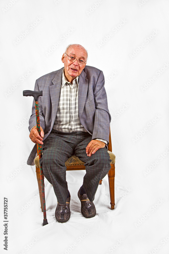 elderly man sitting in his armchair with walking stick elderly man sitting in his armchair with walking stick
