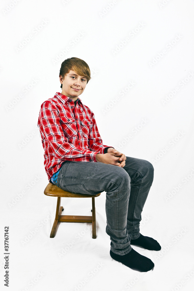 friendly looking young boy with red shirt sitting on a wooden sc