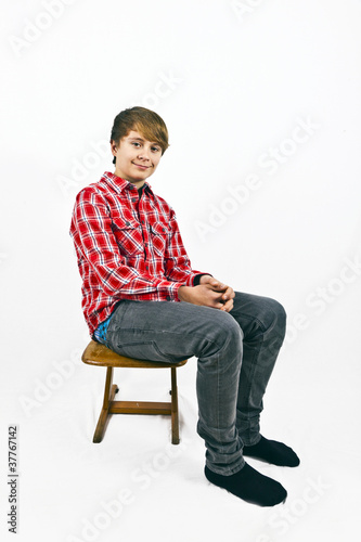 friendly looking young boy with red shirt sitting on a wooden sc © travelview