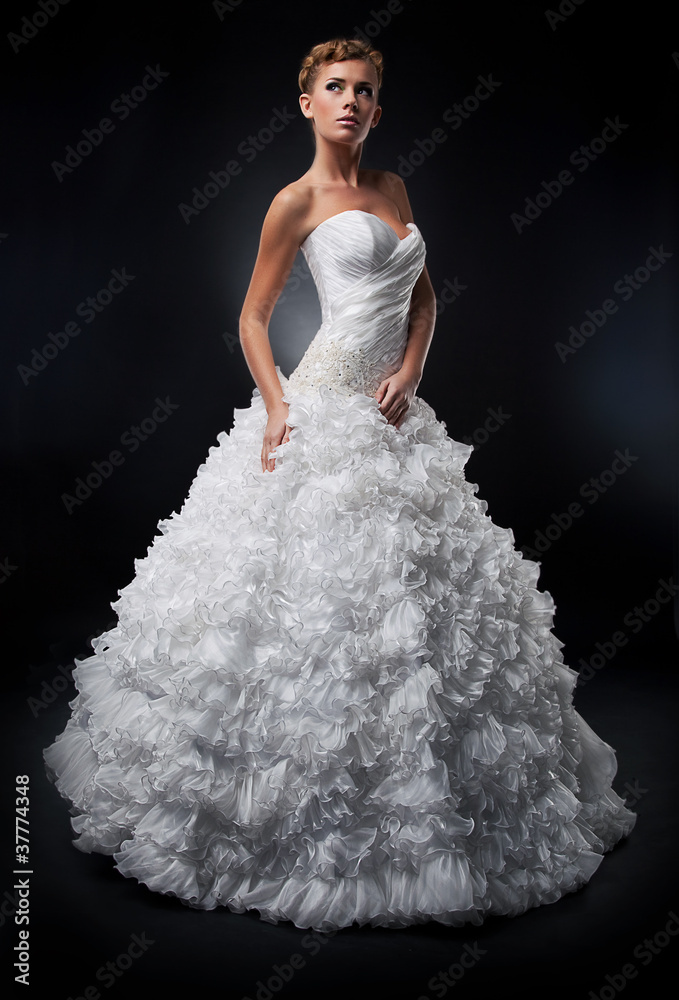 Fototapeta premium Pretty bride in white nuptial dress posing in studio