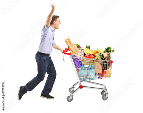 Euphoric man pushing a shopping cart full with food