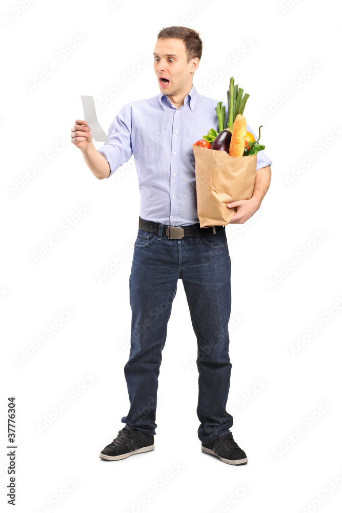 Surprised man looking at store receipt and holding a paper bag Surprised man looking at store receipt and holding a paper bag