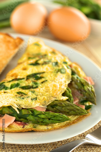 Green asparagus and ham omelet with eggs in the back