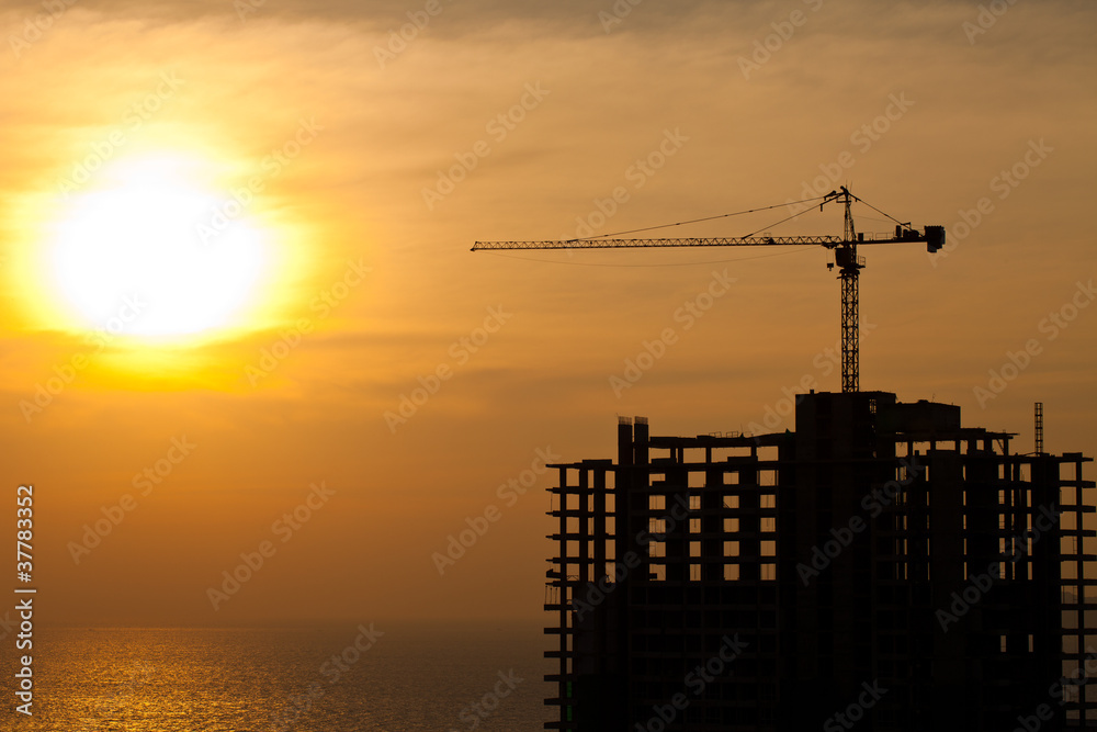 Construction cranes and building silhouettes with sunset