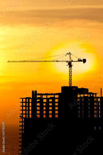 Construction cranes and building silhouettes with sunset