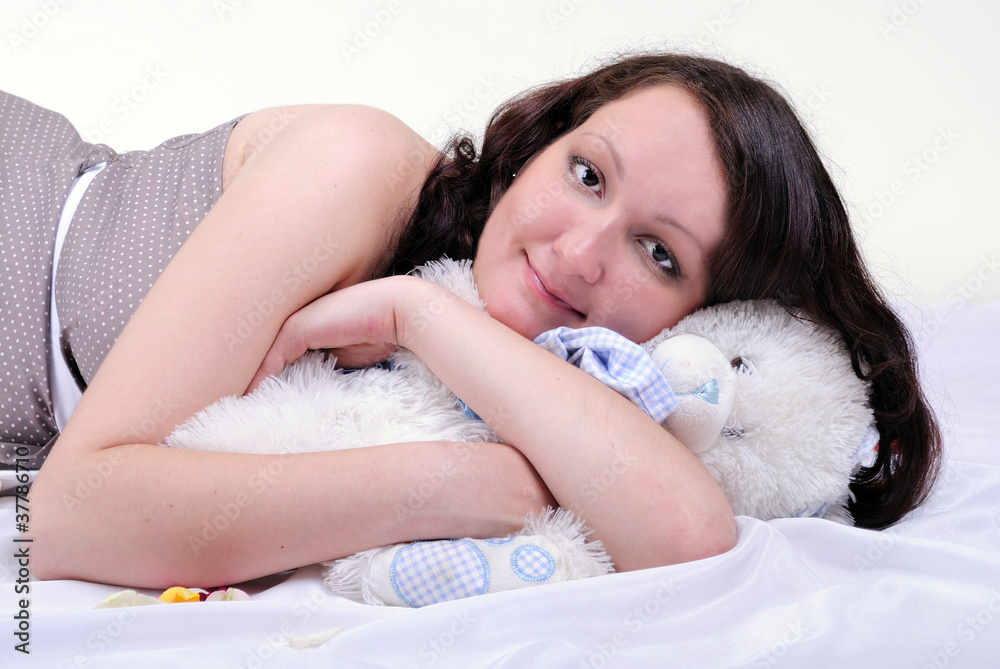 The young pregnant girl with a white teddy bear The young pregnant girl with a white teddy bear