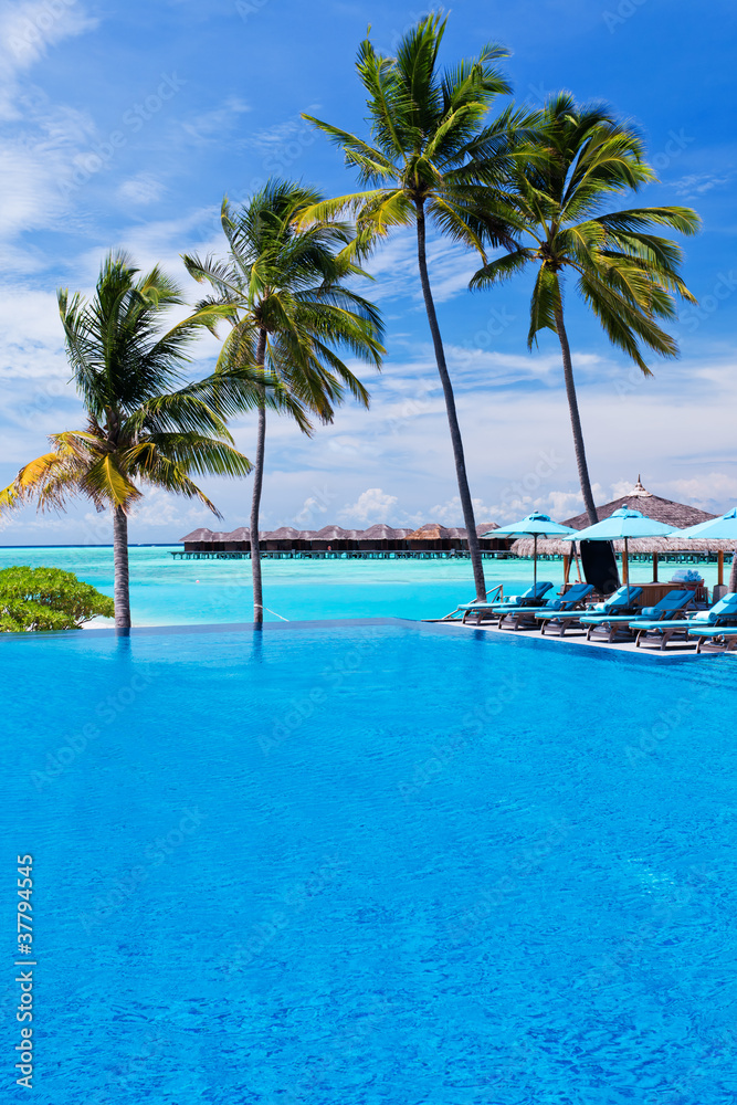 Infinity pool with umbrellas and palm trees over lagoon