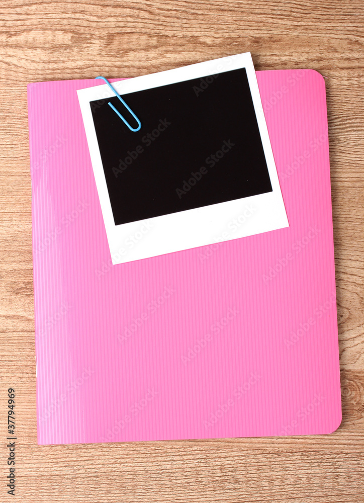 Photo paper and pink notebook on wooden background Photo paper and pink notebook on wooden background