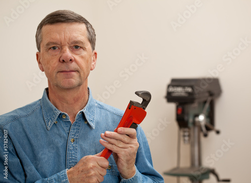 Senior man holding a large wrench © steheap