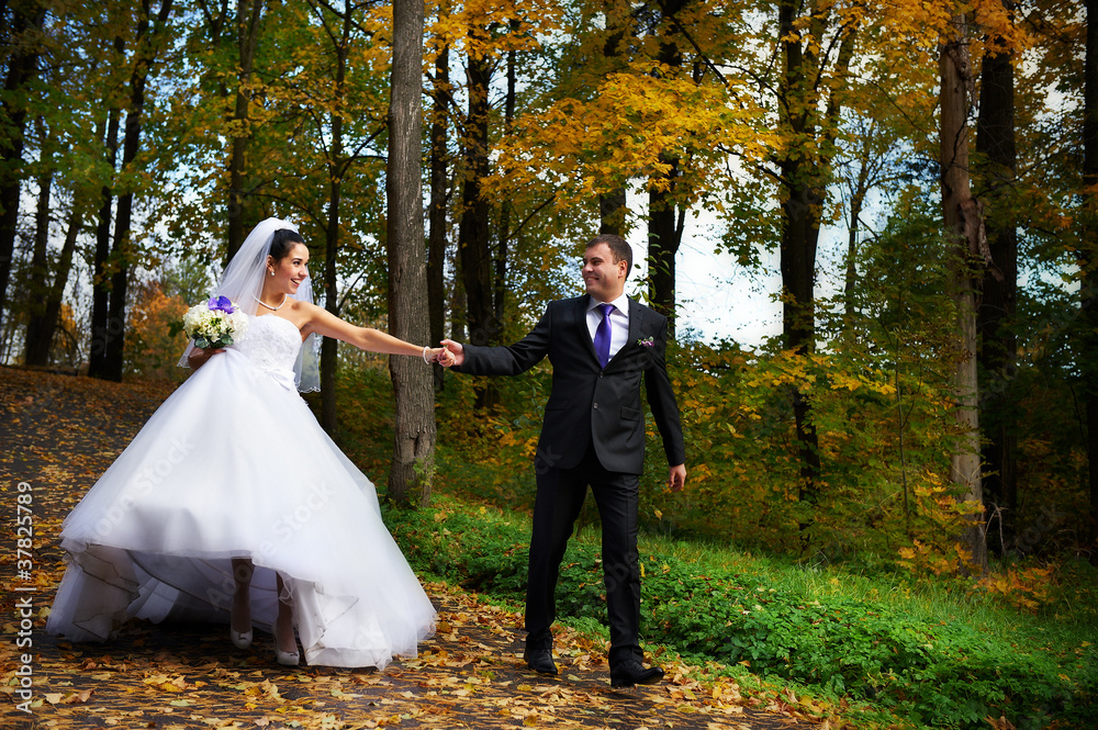 Happy bride and groom walking in autumn park Happy bride and groom walking in autumn park