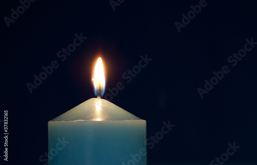 Close up of burning candle against dark blue background