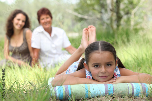 girl relaxing in park with mother and grandma