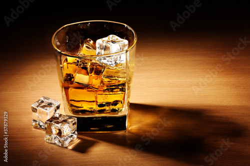 glass of scotch whiskey and ice on wooden table