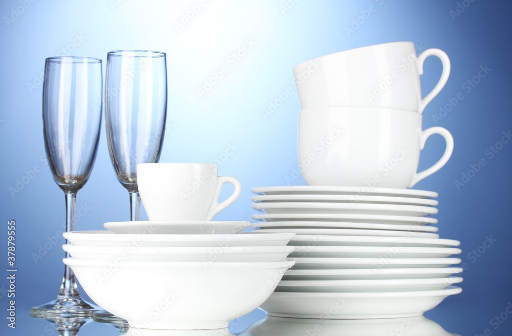 empty bowls, plates, cups and glasses on blue background empty bowls, plates, cups and glasses on blue background