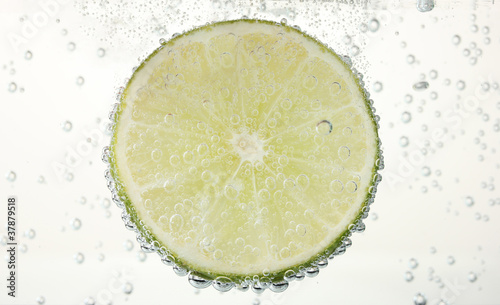 slice of lime in the water with bubbles