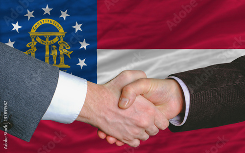 businessmen handshake after good deal in front of georgia flag