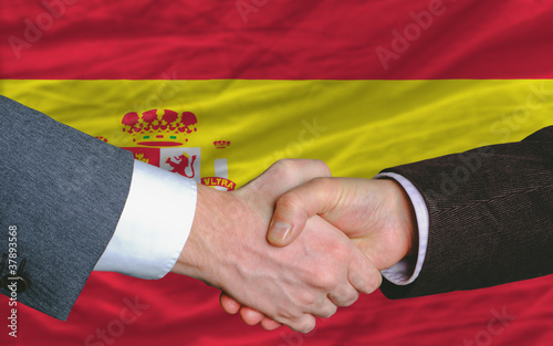 businessmen handshake after good deal in front of spain flag