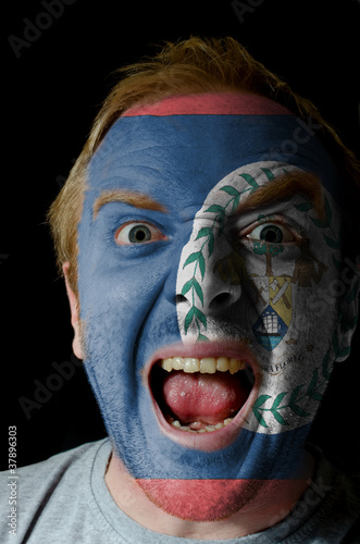 Face of crazy angry man painted in colors of Belize flag