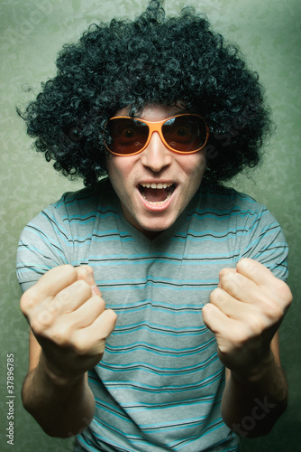crazy young guy in afro curly wig with eyeglasses