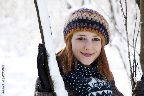 Beautiful young red-haired woman in winter park