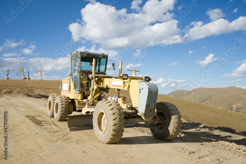 Road building machine with highland landscape