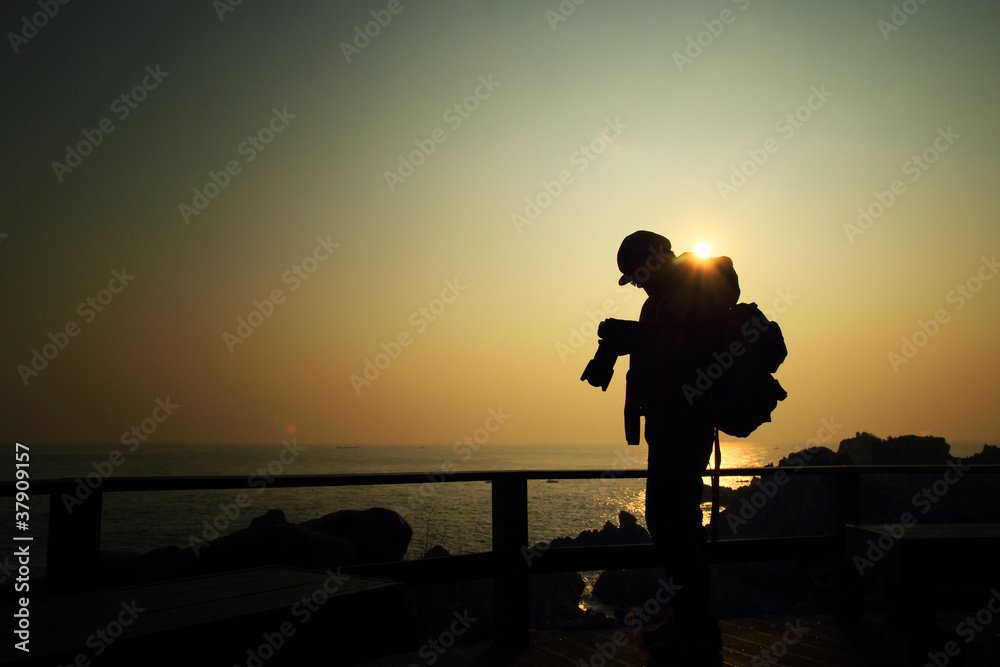 Man is taking a picture from the sunrise on the island and revie