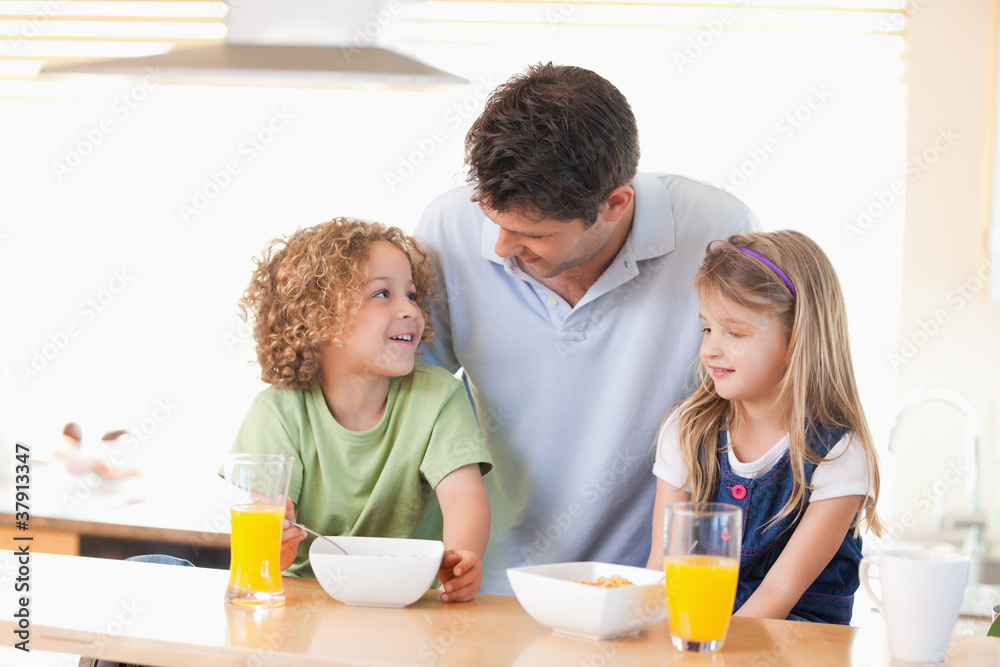 Smiling father with his children having breakfast