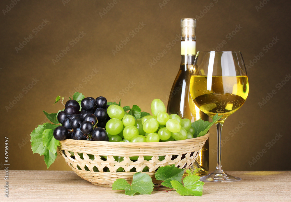 Bottle of wine, glass and grapes in basket on yellow background