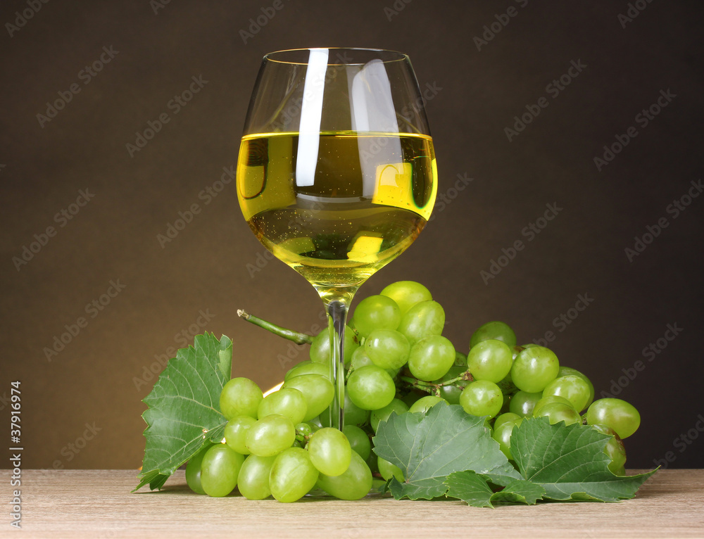 Glass of wine and grapes on yellow background