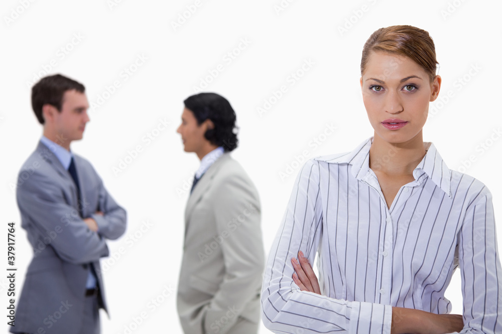 Businesswoman with talking colleagues behind her Businesswoman with talking colleagues behind her