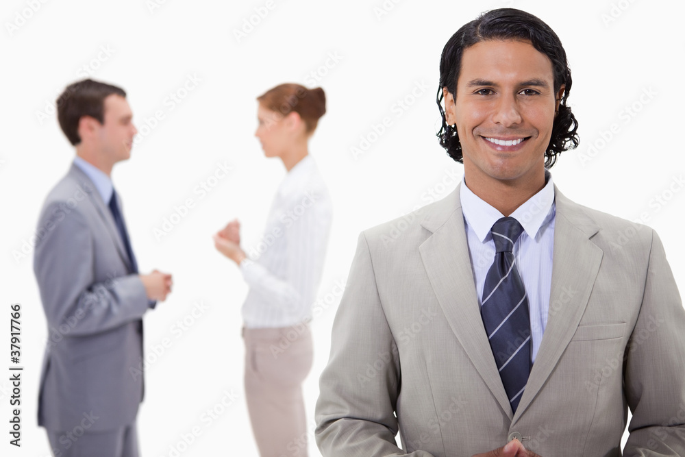 Businessman with talking colleagues behind him Businessman with talking colleagues behind him