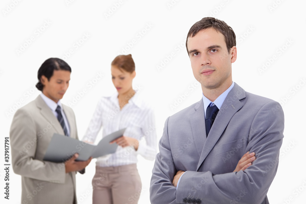 Young businessman with talking colleagues behind him Young businessman with talking colleagues behind him