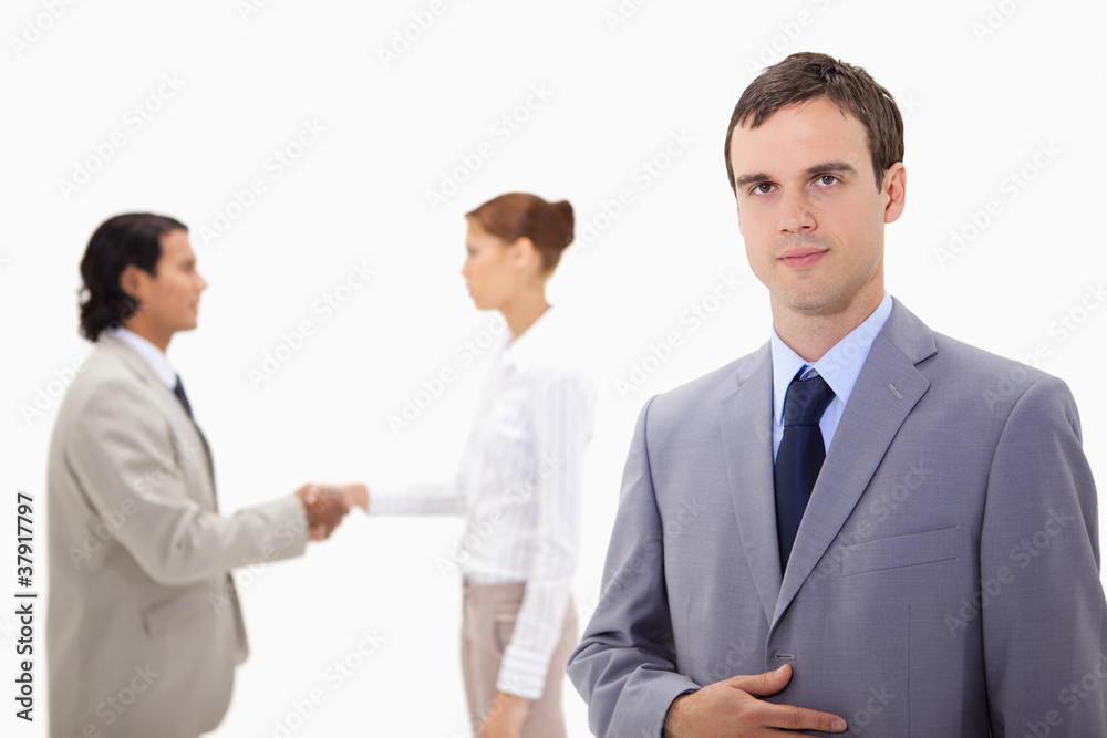 Businessman with hand shaking colleagues behind him