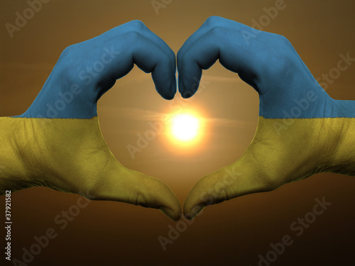 Heart and love gesture by hands colored in ukraine flag during b