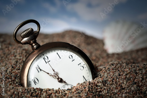 .Old pocket watch buried in sand