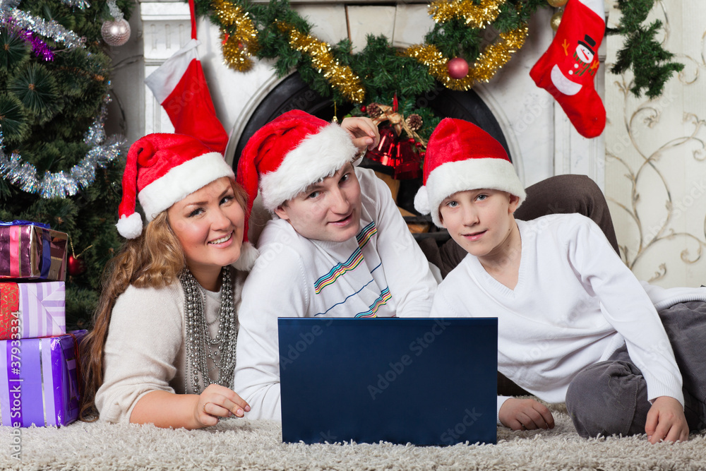 Family with notebook near Christmas tree.