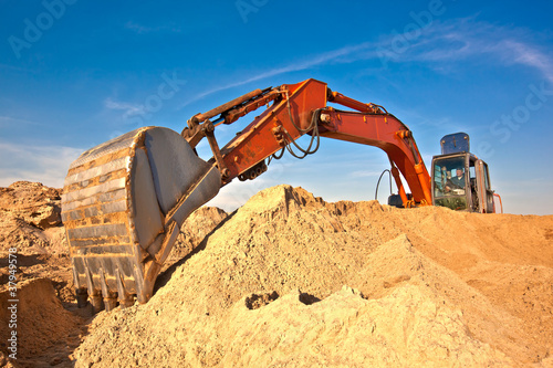 Excavator during earth moving works at sandpit photo