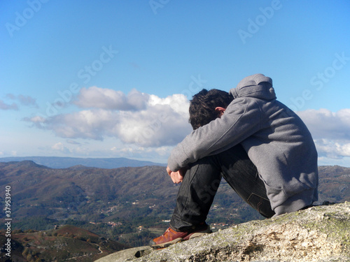 young man sitting on the top of a mountain