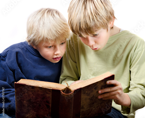 2 blonde boys reading fascinated together in an old book