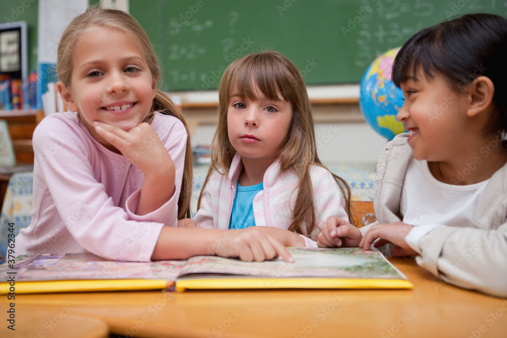 Schoolgirls reading a fairy tale to their classmate Schoolgirls reading a fairy tale to their classmate