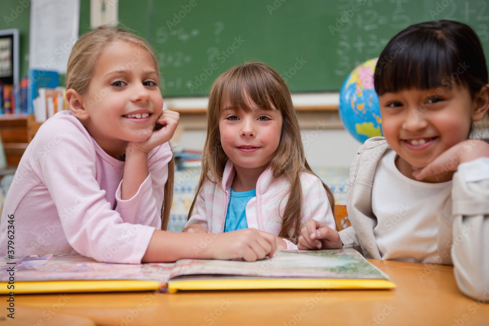 Happy schoolgirls reading a fairy tale to their classmate Happy schoolgirls reading a fairy tale to their classmate