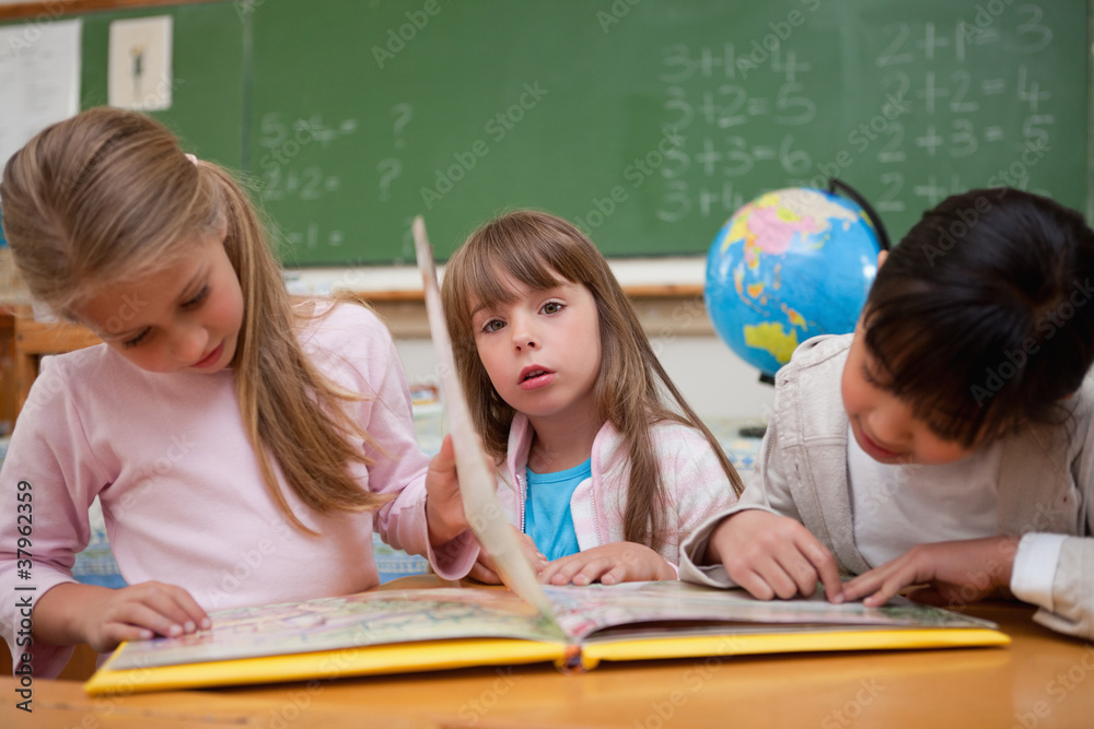 Cute schoolgirls reading a fairy tale to their classmate Cute schoolgirls reading a fairy tale to their classmate