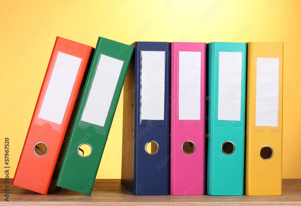 bright office folders on wooden table on yellow background bright office folders on wooden table on yellow background