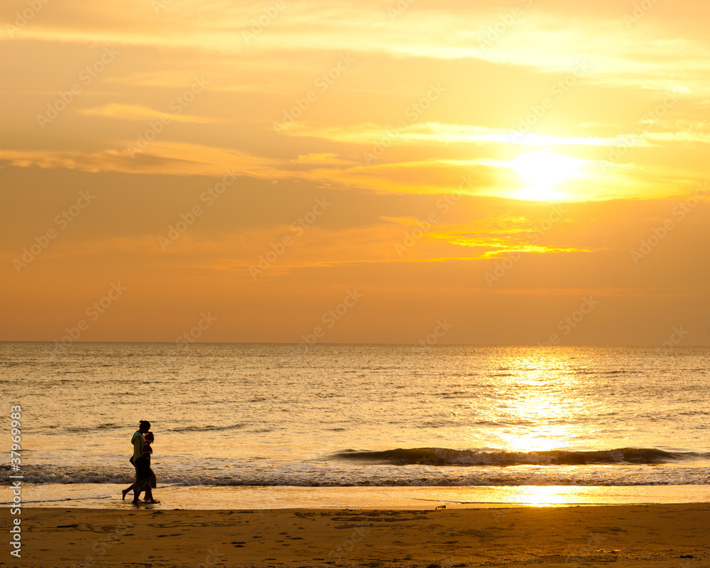 Happy family walking on the beach in the morning with golden sky color