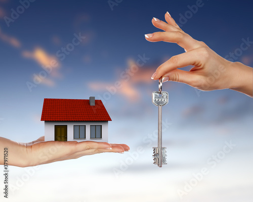 Human hands and house against blue sky