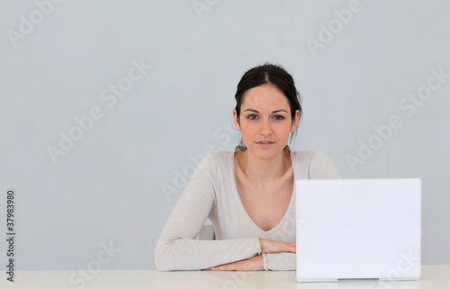 Jeune femme avec ordinateur portable sur fond gris photo