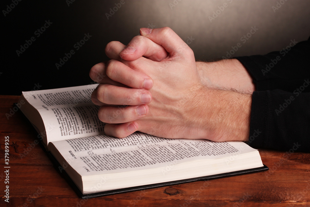 Naklejka premium Hands folded in prayer over a Holy bible